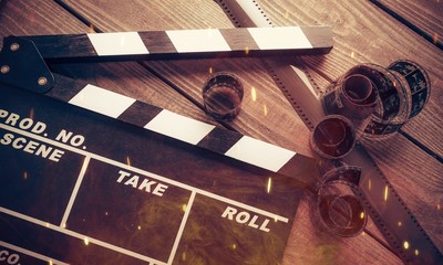 Movie clapper board and film tapes on wooden background