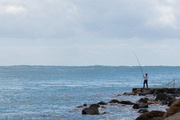 Wall Mural - a man fishing in the sea sunny summer time