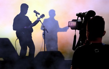 Wall Mural - Cameraman recording and broadcasting live concerts on on stage using video camera.