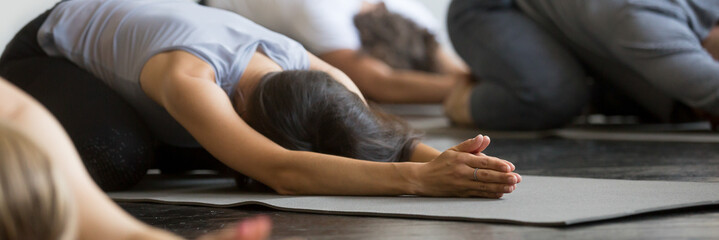 Sporty girls guys practicing Child exercise doing Balasana yoga pose