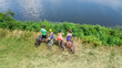 © Iuliia Sokolovska - Family on bikes cycling outdoors, active parents and kids on bicycles, aerial view of happy family with children relaxing near beautiful river from above, sport and fitness concept