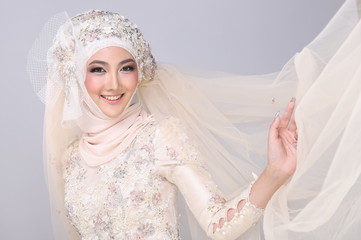 Asian Charming muslim arabic bride in Lace Bead Embroidery creammy yellow wedding dress and hijab headscarf, close-up on Fashion Make up Eyes Face, studio lighting grey background isolated.