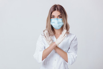 Portrait of woman doctor with face mask and white medical gloves shows stop sign