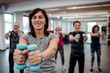 © Halfpoint - Group of cheerful seniors in gym doing exercise with dumbbells.