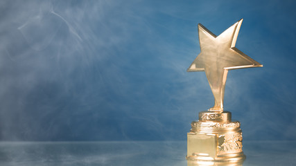 Wall Mural - gold star trophy in smoke, blue background