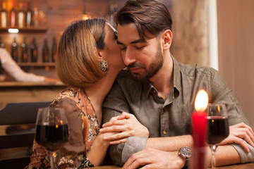 Young woman gently kissing the cheek of her boyfriend on a dinner date