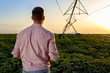 © Zoran Zeremski - Young farmer holding tablet in his hands and adjusts irrigation system on soybean field at sunset.