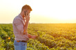 © Zoran Zeremski - Young farmer in filed examining soybean corp and talking at phone.