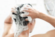 Closeup young man washing hair with with shampoo in the bathroom, health care concept