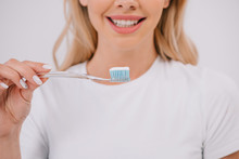 Partial View Of Smiling Woman Holding Toothbrush Isolated On White