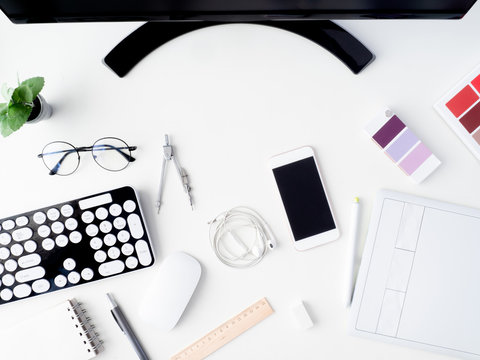 top view of office desk work space with notebook, graphic tablet, smartphone and gadget on white background with copy space, graphic designer, Creative Designer concept.