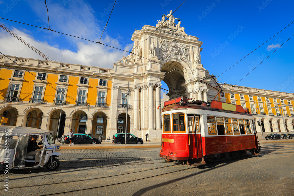 Touristic tram at Praca do Comercio (Commercial Square) near Triumphal Arch of Rua Augusta. Sunny day in famous tourist place of Lisboa - obrazy, fototapety, plakaty 
