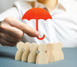 Boss holding a red umbrella and defending his team with a gesture of protection. Security and safety in a business team. Life insurance. Customer care, care for employees. Selective focus