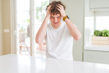 Wall Mural - Young handsome man wearing white t-shirt at home suffering from headache desperate and stressed because pain and migraine. Hands on head.