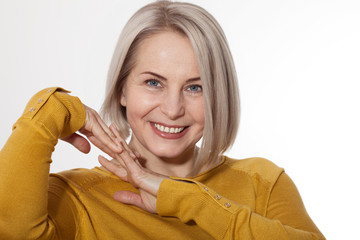Wall Mural - middle aged blonde emotionally posing in a studio. happy woman in yellow bright sweater on white bac