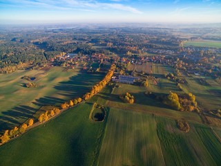 Poster - Country road with colorful maple trees through the hilly terrain during the autumn season, Pozezdrze town in the background, Mazury, Poland