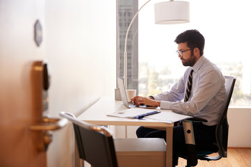 Wall Mural - Businessman Sitting At Desk Working On Laptop In Modern Office