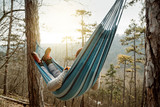 Fototapeta  - Young happy man relaxing lying in hammock on top of mountain.