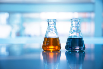 Wall Mural - two glass flasks with orange and black solution in chemical science laboratory background