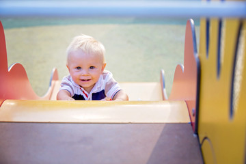 Wall Mural - Little baby boy, playing on playground on sunset