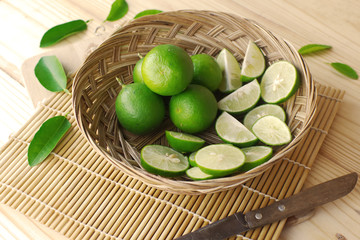 Canvas Print - Green lemon with green lemon slice in basket on bamboo mat.