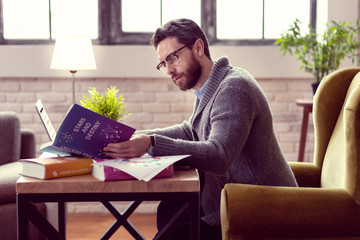 serious nice man studying the encyclopedia about stars