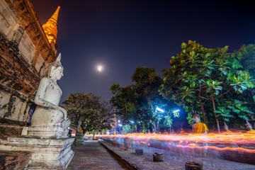 Wall Mural - Buddhists people walking with lighted candles in hand around a ancient temple