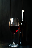 Fototapeta Panele - Bottle of wine and a glass of wine on a dark background