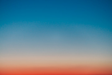 Wall Mural - Predawn clear sky with red horizon and blue atmosphere. Smooth orange blue gradient of dawn sky. Background of beginning of day. Heaven at early morning with copy space. Sunset, sunrise backdrop.