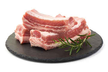 Wall Mural - Raw fresh pork ribs with rosemary on a slate shale plate, close-up, isolated on white background