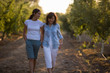 © Erickson Stock - A mother and her grown up daughter walking through an orchard