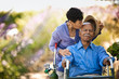 © Erickson Stock - Happy senior man in a wheelchair being kissed on the head by his wife in a garden.