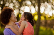 © Erickson Stock - Mid adult woman grinning at her daughter as she holds her in the forest.