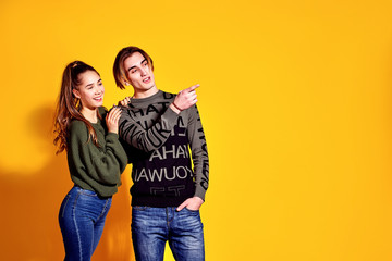 Couple in casual clothes posing in jeans type commercial fashion style on yellow wall