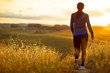 © Erickson Stock - Energetic young woman jogging through the rural countryside at sunset.