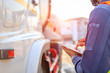 © KM.Photo - Truck drivers hand holding tablet checking the product list,Driver writing electronic log books,spot focus.