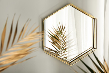 Mirror and golden tropical leaves in room