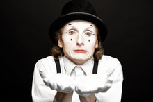 Close-up Portrait Of A Pantomime With White Facial Makeup Posing With Expressive Emotions On The Black Background
