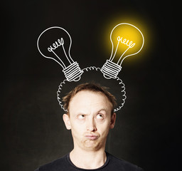 Man with light bulb on blackboard background. Brainstorming and idea concept