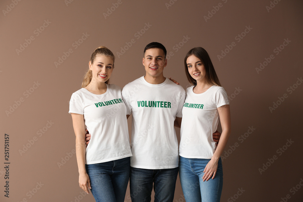 Team of young volunteers on color background