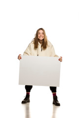 Wall Mural - Young model in hoodie shows an empty advertising board on white background