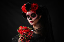 Young Woman With Painted Skull On Her Face For Mexico's Day Of The Dead Against Dark Background