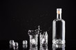 bottle of vodka with glasses and splashes on a black background