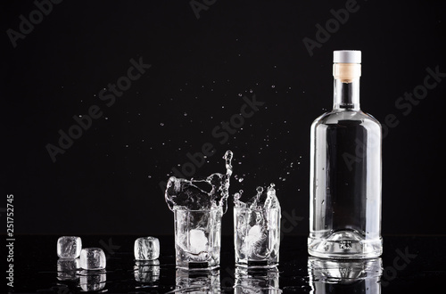 Cuadros en Lienzo bottle of vodka with glasses and splashes on a black background