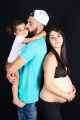 Wall Mural - Happy family father and child girl daughter embracing belly of mother pregnant