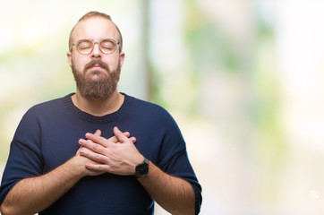 Sticker - Young caucasian hipster man wearing sunglasses over isolated background smiling with hands on chest with closed eyes and grateful gesture on face. Health concept.