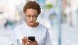 © Krakenimages.com - Young african american woman using smartphone over isolated background scared in shock with a surprise face, afraid and excited with fear expression