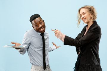 Concept of partnership in business. Young happy smiling man and woman standing against blue background at studio