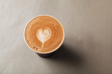 Wall Mural - Paper cup of latte or cappuccino with patterned heart latte art on a grey background. Coffee to take away, coffee to go