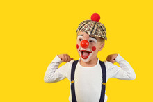 Portrait Funny Child.Cheerful Boy,costume Clown,red Nose,makeup.Emotional Face Little Comic Kid.Happy Baby Isolated Yellow Background.1 April Fool's Day Celebration. Concept Birthday, Holiday, Humor.